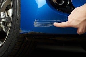 a mechanic is pointing to an identified scratch on car